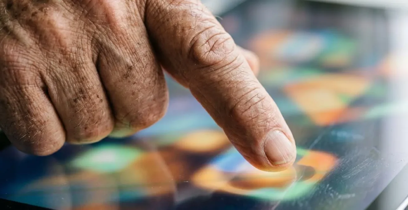Main d'une personne âgée interagissant avec précision sur un écran tactile aux zones de clic élargies